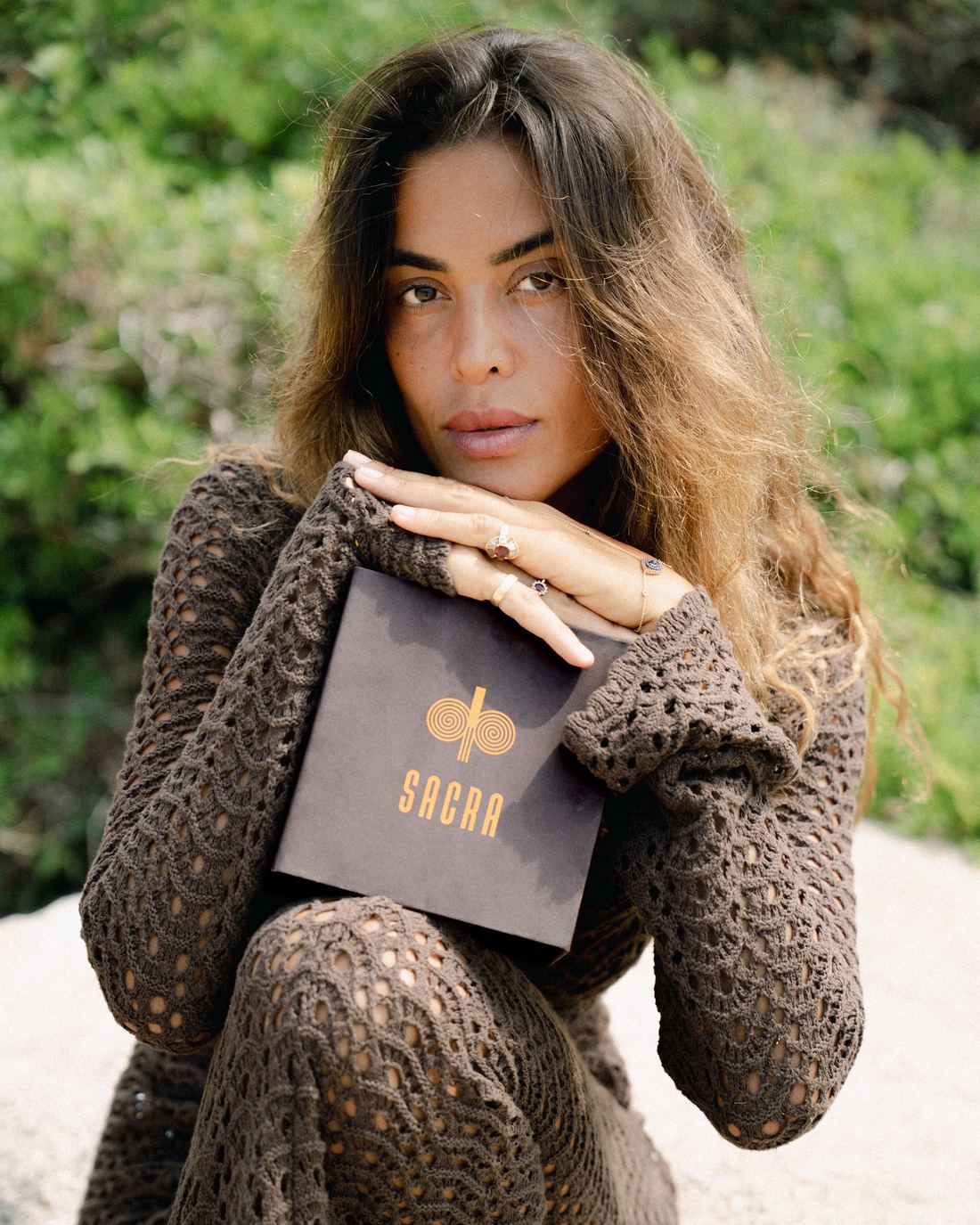 A woman holding the SACRA box to her chin, sunlight on her face
